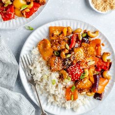 two plates filled with rice and vegetables on top of a white tablecloth next to silverware