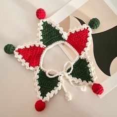 a crocheted christmas ornament hanging from a white frame with red and green decorations