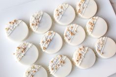 nine decorated cookies sitting on top of a white plate with gold sprinkles