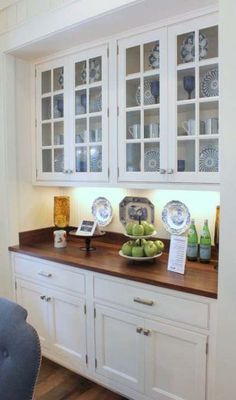 a kitchen with white cabinets and wooden counter tops, blue chairs and plates on the counters