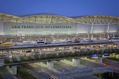 the san francisco international airport terminal is lit up at night, with cars parked in front