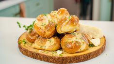 a pile of bread rolls sitting on top of a cutting board with cheese and herbs