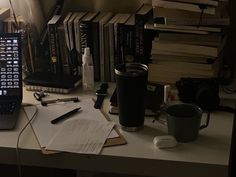 a laptop computer sitting on top of a desk next to a pile of books and papers