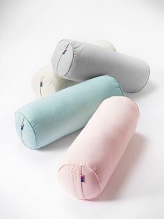 three pillows sitting next to each other on top of a white surface, one pink and one blue