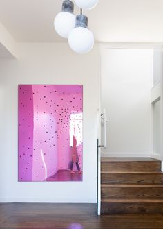 a pink painting is hanging on the wall next to some stairs and wooden flooring