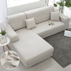 a white couch sitting on top of a gray rug next to a table with a laptop