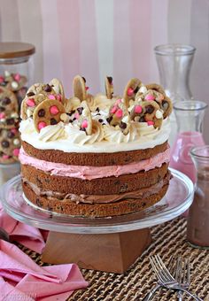 a cake with white frosting and pink icing is on a glass platter