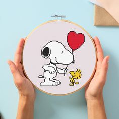 someone holding up a cross - stitch pattern with a dog and heart in the middle