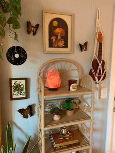 a shelf with some plants and pictures on the wall above it, along with other items