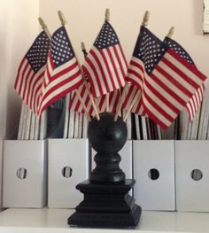 several american flags are placed in a black vase