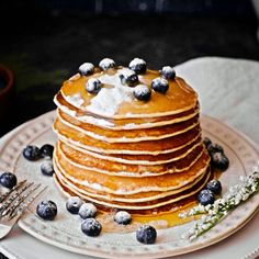 a stack of pancakes covered in blueberries and powdered sugar