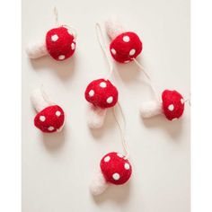 three red and white mushrooms are hanging from strings