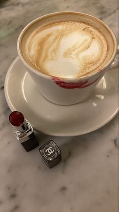 a cappuccino on a saucer with lipstick next to it