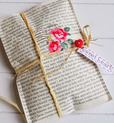 an open book with flowers on it and a tag attached to the pages that have been folded