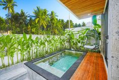 an outdoor jacuzzi with wooden decking and palm trees in the back ground