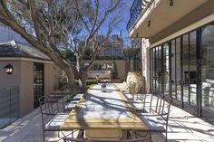 an outdoor dining area with tables and chairs on the side of the building, surrounded by trees