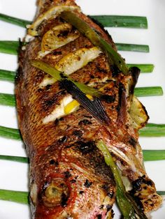 grilled fish on a white plate with green onions