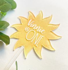 a sun shaped cake topper with the words wine and one on it next to some leaves