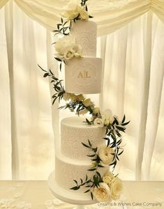 three tiered wedding cake with white flowers and greenery