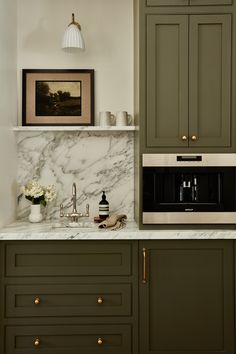 a kitchen with green cabinets and marble counter tops, including a built - in microwave