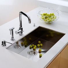 a kitchen sink filled with green olives next to a faucet and counter top