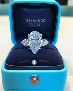 a diamond ring in a blue box with the lid open to show it's center stone