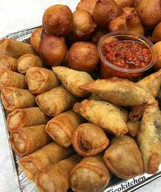 there are many different types of pastries on the platter with dipping sauces