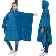 two women in blue ponchies are standing next to each other and one is holding a large towel