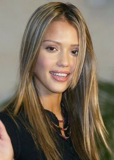 a beautiful young lady with long brown hair and wearing a black top smiling at the camera