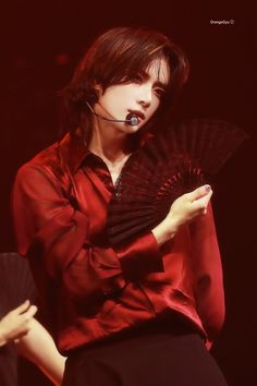 a woman in a red shirt holding a black fan