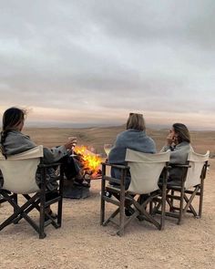 three people sitting around a campfire in the desert