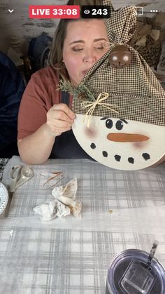 a woman is making a snowman mask out of wood