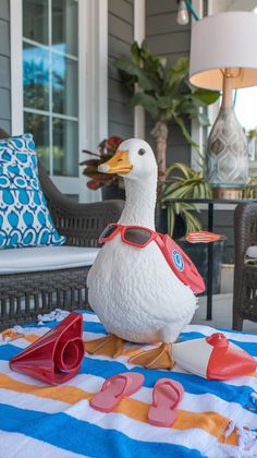 a duck with sunglasses and flip flops sitting on a towel outside the house,