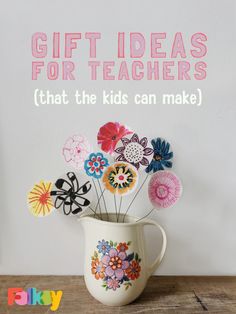 a vase filled with paper flowers sitting on top of a wooden table next to a white wall