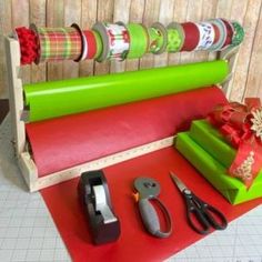 some wrapping tape and scissors are sitting on a red mat next to a green box