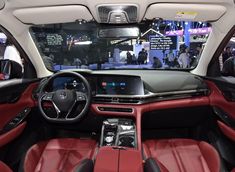 the interior of a car with red leather seats and steering wheel, on display at an auto show