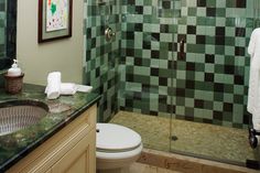 a bathroom with green tiles on the shower wall