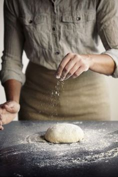 a woman sprinkling flour on top of a doughnut