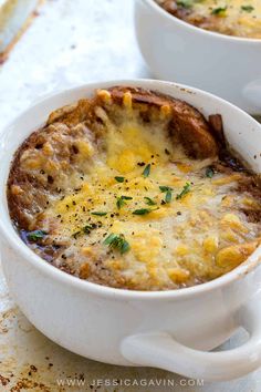 two white bowls filled with baked potato casserole on top of a wooden table