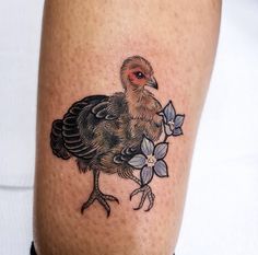 a tattoo on the leg of a man with a bird and flowers in it's beak