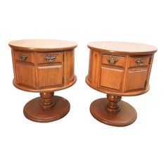 two wooden side tables sitting next to each other on top of pedestals with drawers