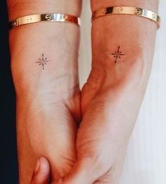 two people holding hands with small tattoos on their wrists