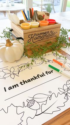 a wooden box filled with markers and pumpkins sitting on top of a white table