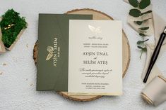 the wedding stationery is laid out on top of a wooden slice with greenery