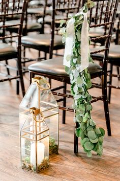 an arrangement of greenery and candles on chairs