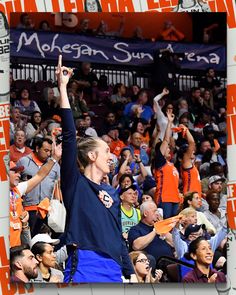 a woman is holding her hand up in the air at a basketball game with an orange and white banner behind her