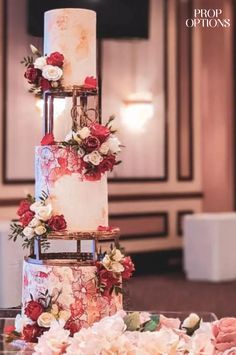 a multi - tiered wedding cake with red and white flowers