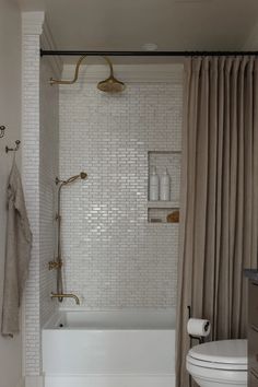 a bathroom with a toilet, bathtub and shower curtained in white tiles on the walls