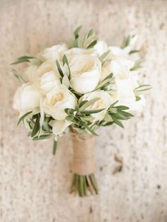 a bouquet of white roses and greenery in a vase on a wall with an ad for cell phone