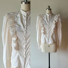 "Vintage 1970s-80's ruffled long sleeve poet blouse by Lasting Impression size small Such an elegant romantic blouse.   Off white light weight silky polyester.  Ruffled front with matching covered buttons.  Long very full puffed sleeves that narrow at the wrists with ruffled hems and double buttons  light shoulder pads.  Tucked back at the waist. 100% polyester made Phillipines  Excellent vintage condition, no flaw noted.  Labeled a size L.  measures more like a size small. To ensure an accurate fit, please refer to the measurements below.  Pictured on a modern size 0 dress form.   Measurements lying flat: Total length: 22\" Bust arm pit to arm pit:  18\" Sleeve length: 26\" Waist: 17\" Hem: 18\" Shoulders: 14\"" Feminine Blouse With Bishop Sleeves And Ruffles, Daywear Blouse With Bishop Sleeves And Ruffles, Daywear Blouse With Ruffles And Bishop Sleeves, Retro Ruffled Blouse For Spring, Spring Victorian Fitted Blouse, Spring Retro Blouse With Ruffles, Spring Victorian Blouse For Formal Occasions, Spring Bishop Sleeve Blouse With Ruffles, Victorian Style Formal Blouse For Spring